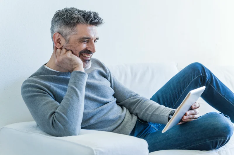 Hombre maduro sonriendo y leyendo un ebook